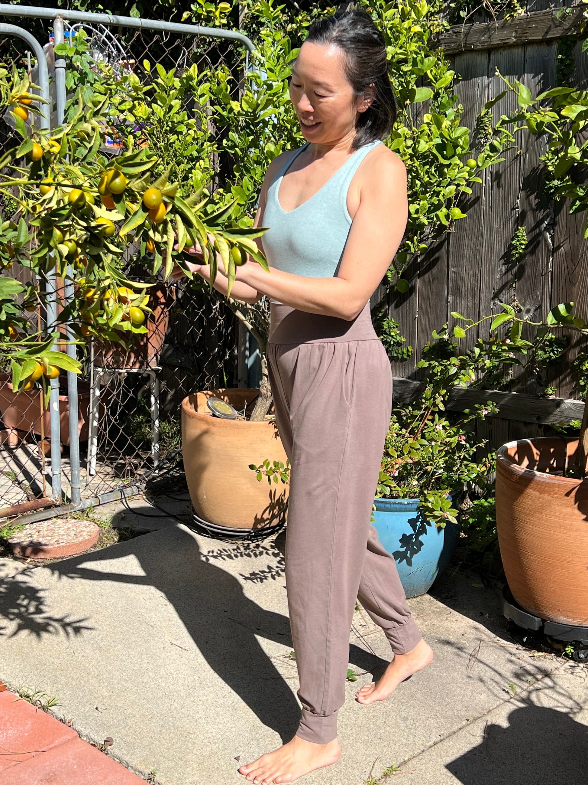 Person gardening in a backyard with plants and pots around
