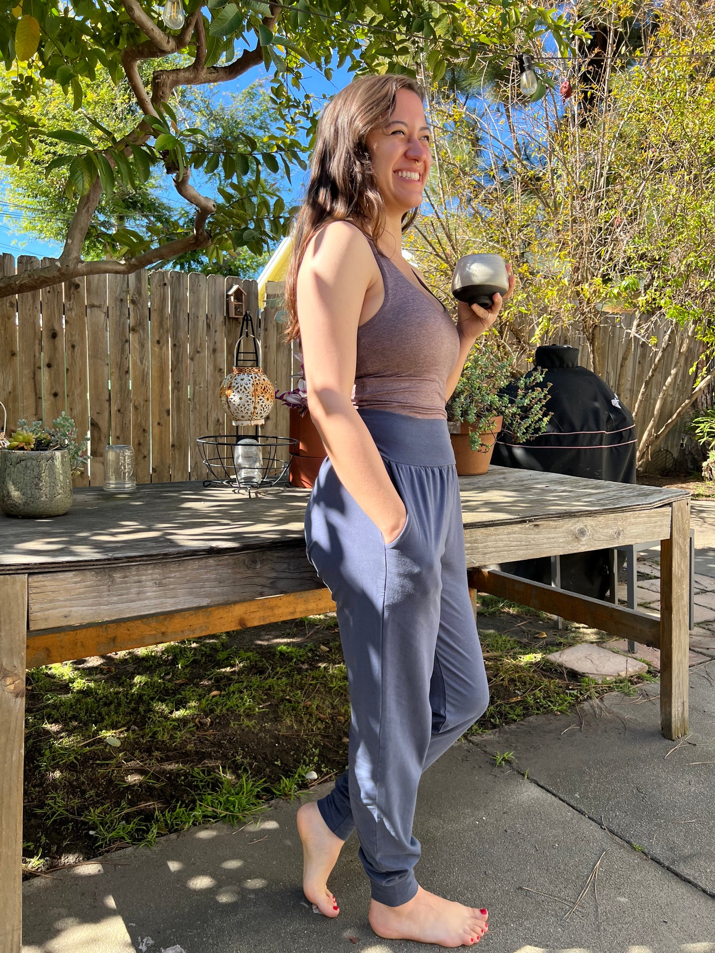 woman wearing yoga pants outdoors with trees and a wooden deck in the background