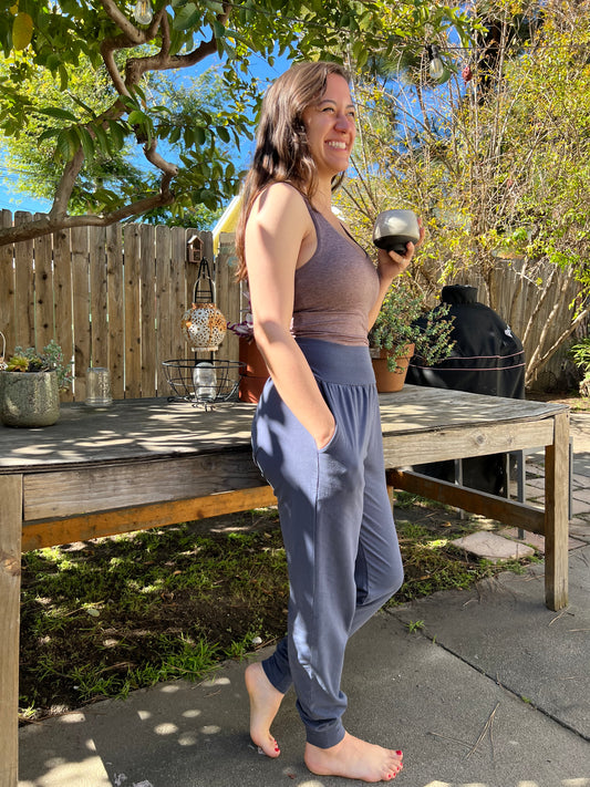 woman wearing yoga pants outdoors with trees and a wooden deck in the background