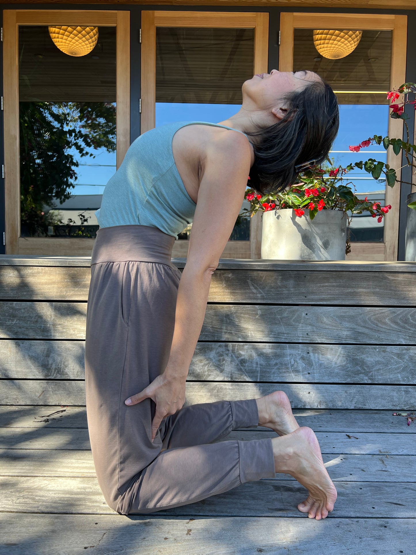 Person practicing yoga on a wooden deck with a decorative plant in the background